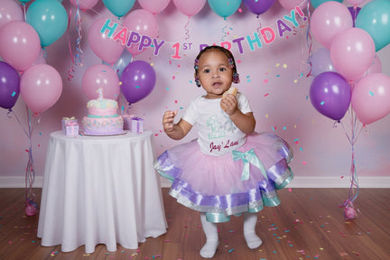 Child wearing a festive outfit with a purple and green skirt, holding a piece of cake.