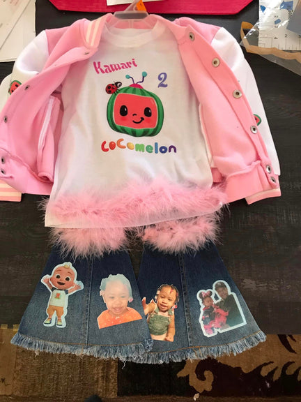 A kid's outfit consisting of a pink jacket with a coccolm3n design and kawaii text, and a denim skirt with cartoon images.